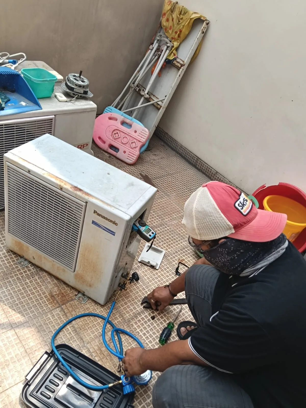 Teknisi Titik Dingin Solusi melakukan perawatan unit AC outdoor